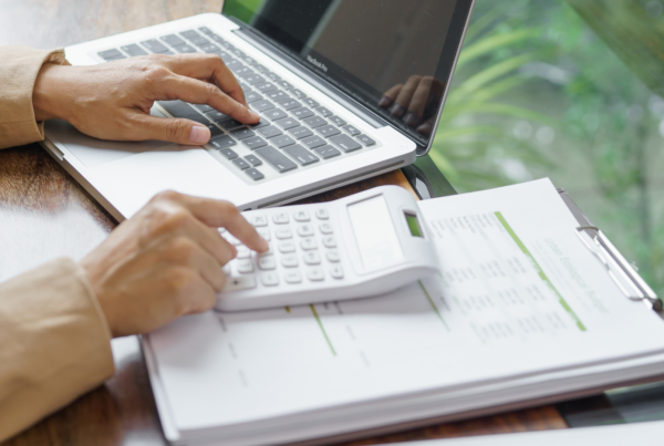 Business owner calculating ATO debt and reviewing financial documents on laptop