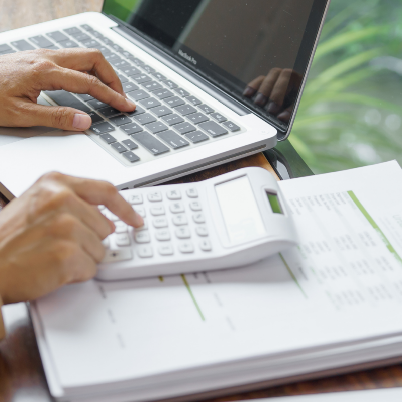 Business owner calculating ATO debt and reviewing financial documents on laptop